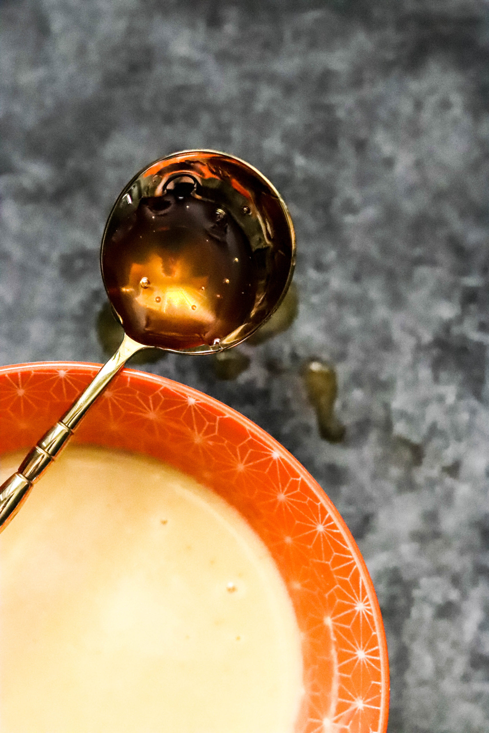 honey on a golden spoon dripping into a bowl of honey mustard sauce.