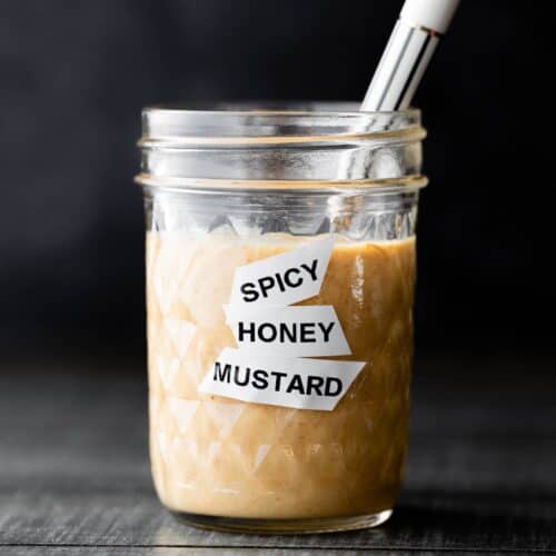 Spicy Honey Mustard Dipping sauce in a glass gar with a white spoon.