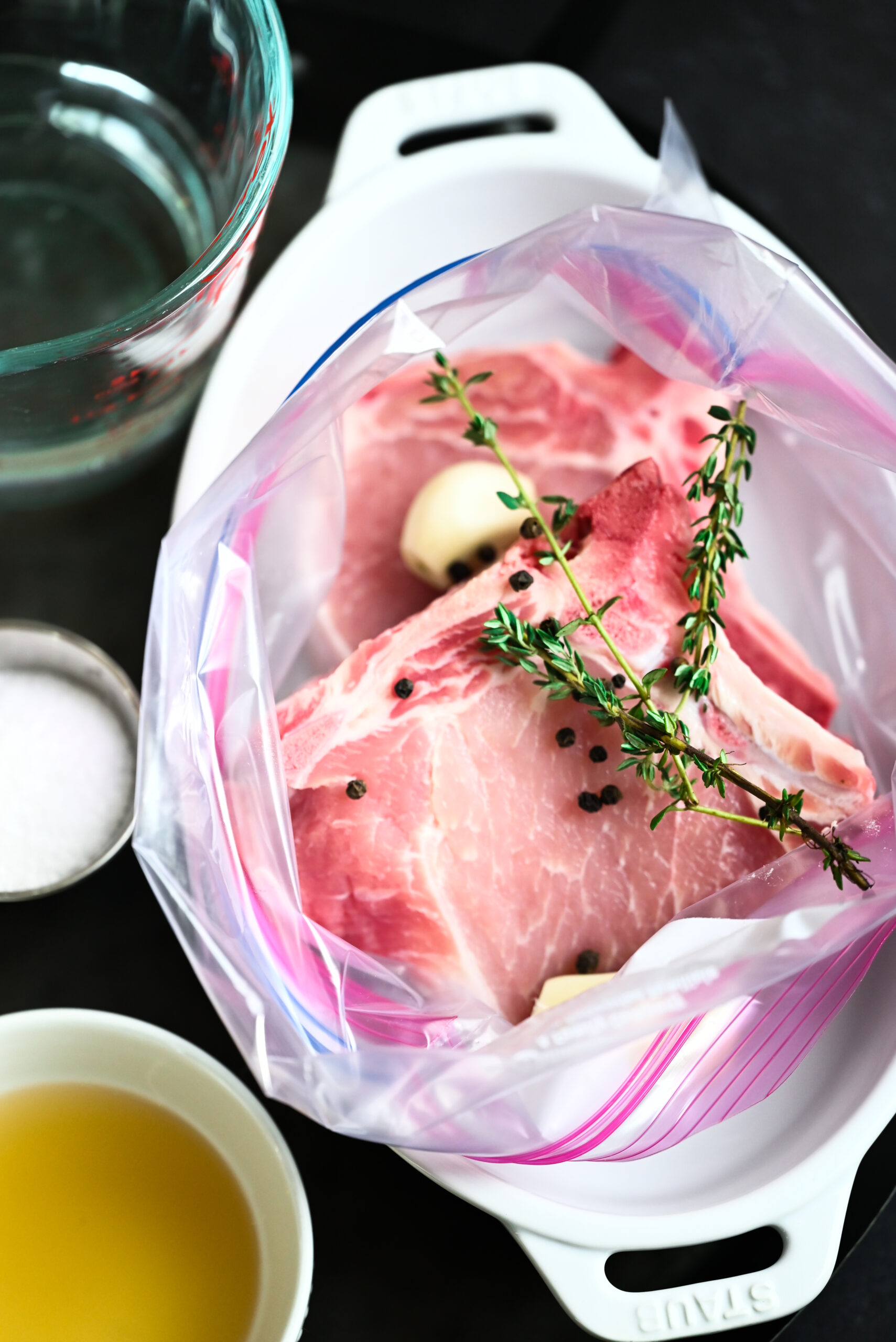 Process photo showing the pork in a bag with rosemary and peppercorns. 