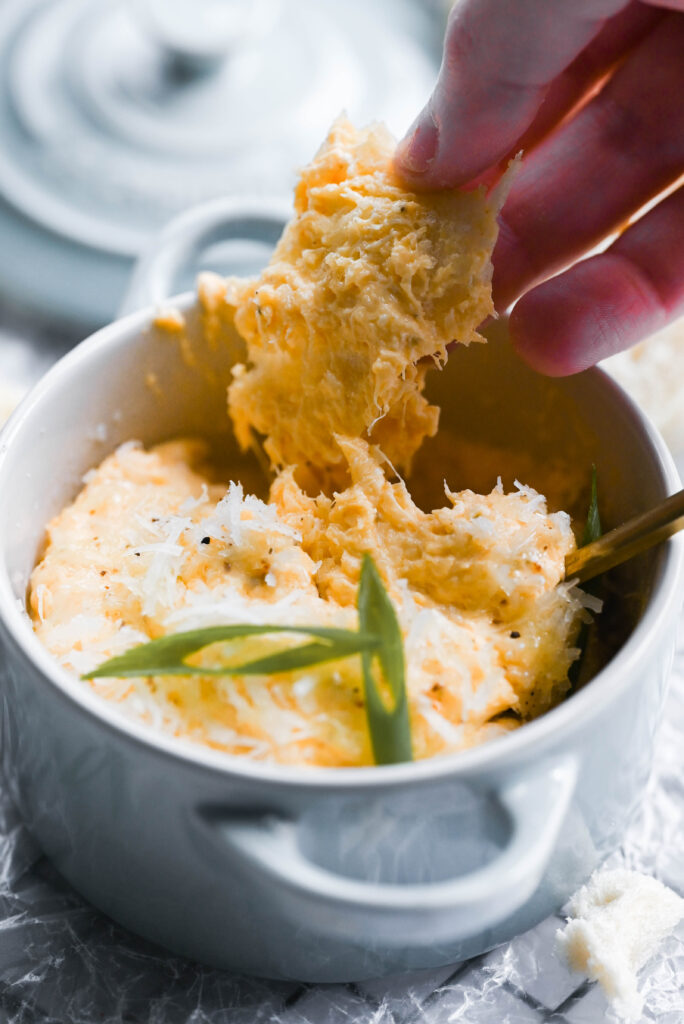 Photo of a baguette in buffalo crab dip. 