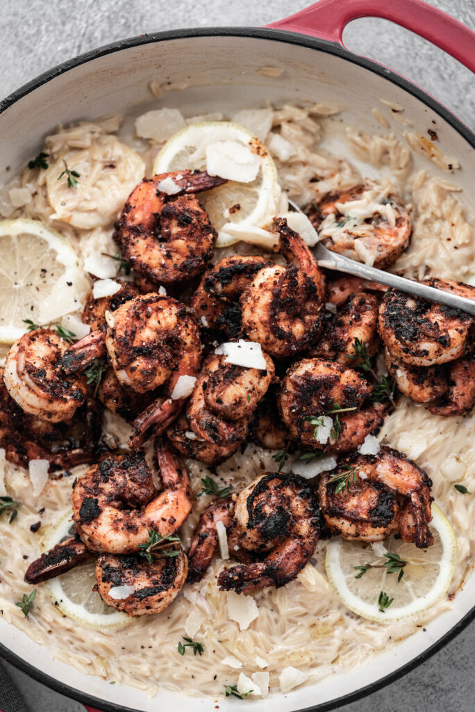 Blackened Shrimp Alfredo with lemon in a red cast iron skillet. 