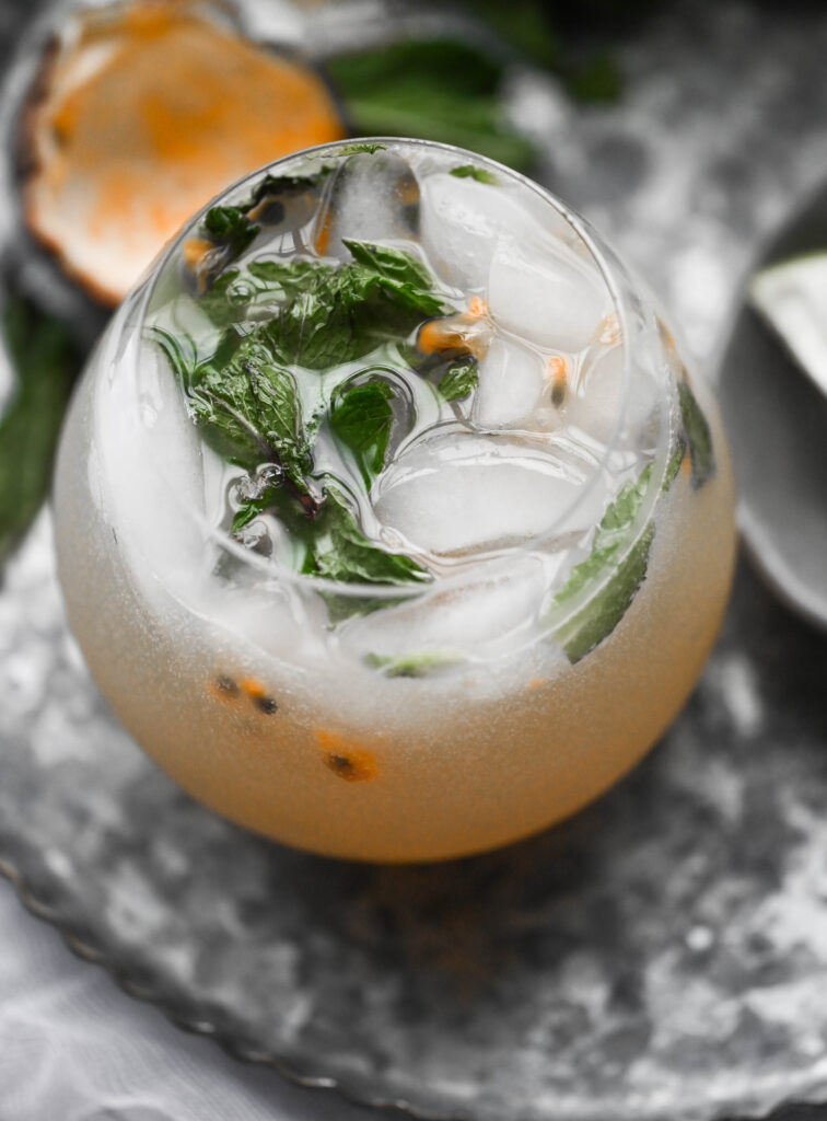 Photo of a passion fruit mojito mocktail with mint leaves for garnish.  