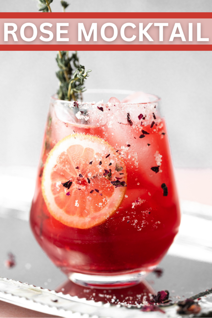 Pinterest pin of a wine glass filled with rose tea mocktail and garnished with a fresh lemon. 