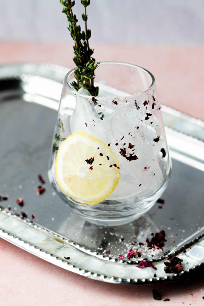 Stemless wine glass garnished with a lemon and pink Himalayan salt. 