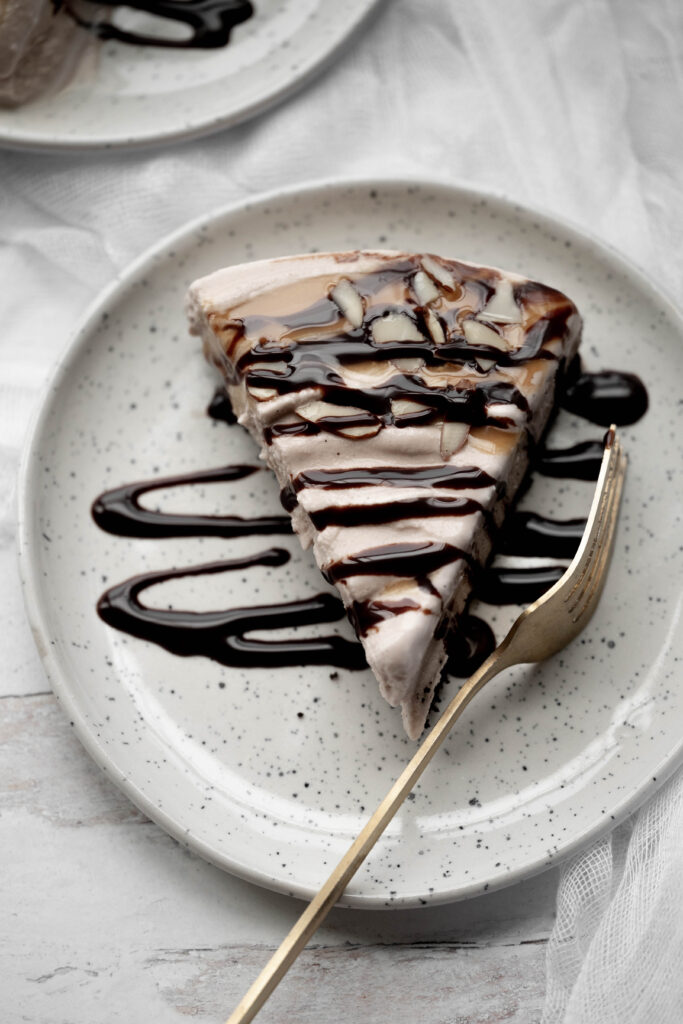 Billy Miner pie on a plate with lots of chocolate drizzle and a gold fork on the side. 