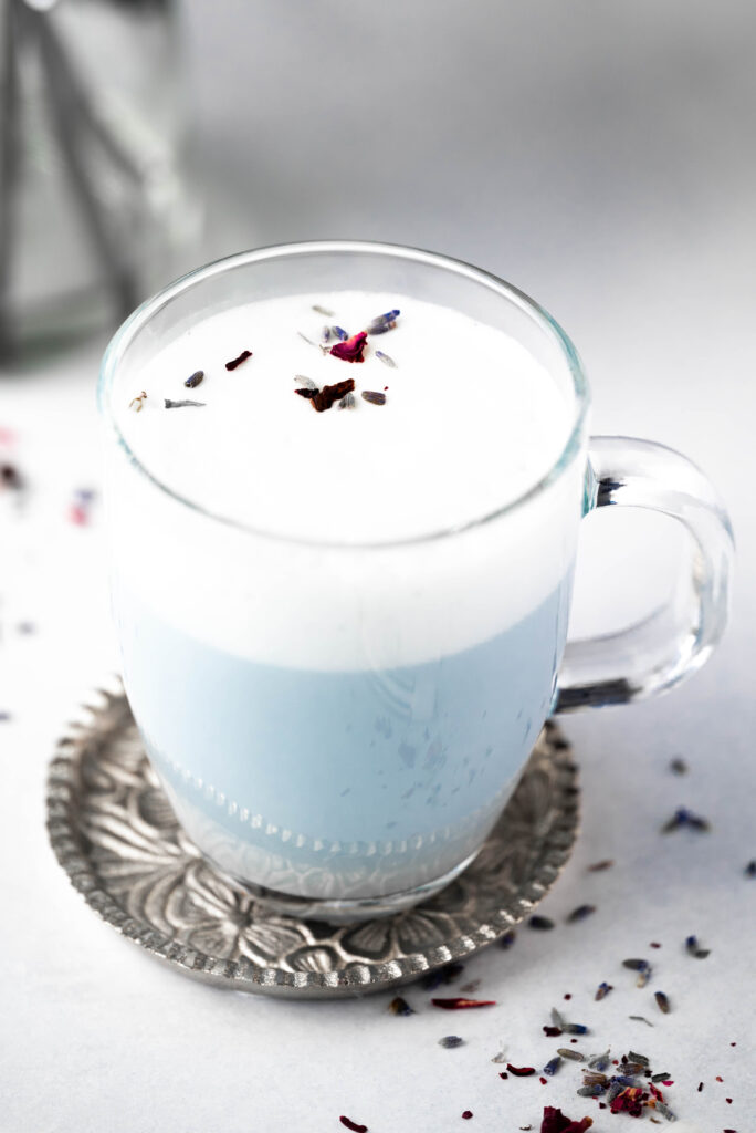 The top of a butterfly pea latte garnished with some lavender flowers. 