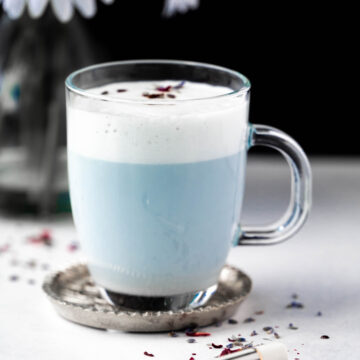 Photo of a Blue mermaid latte with foam and lavender flowers as garnish.