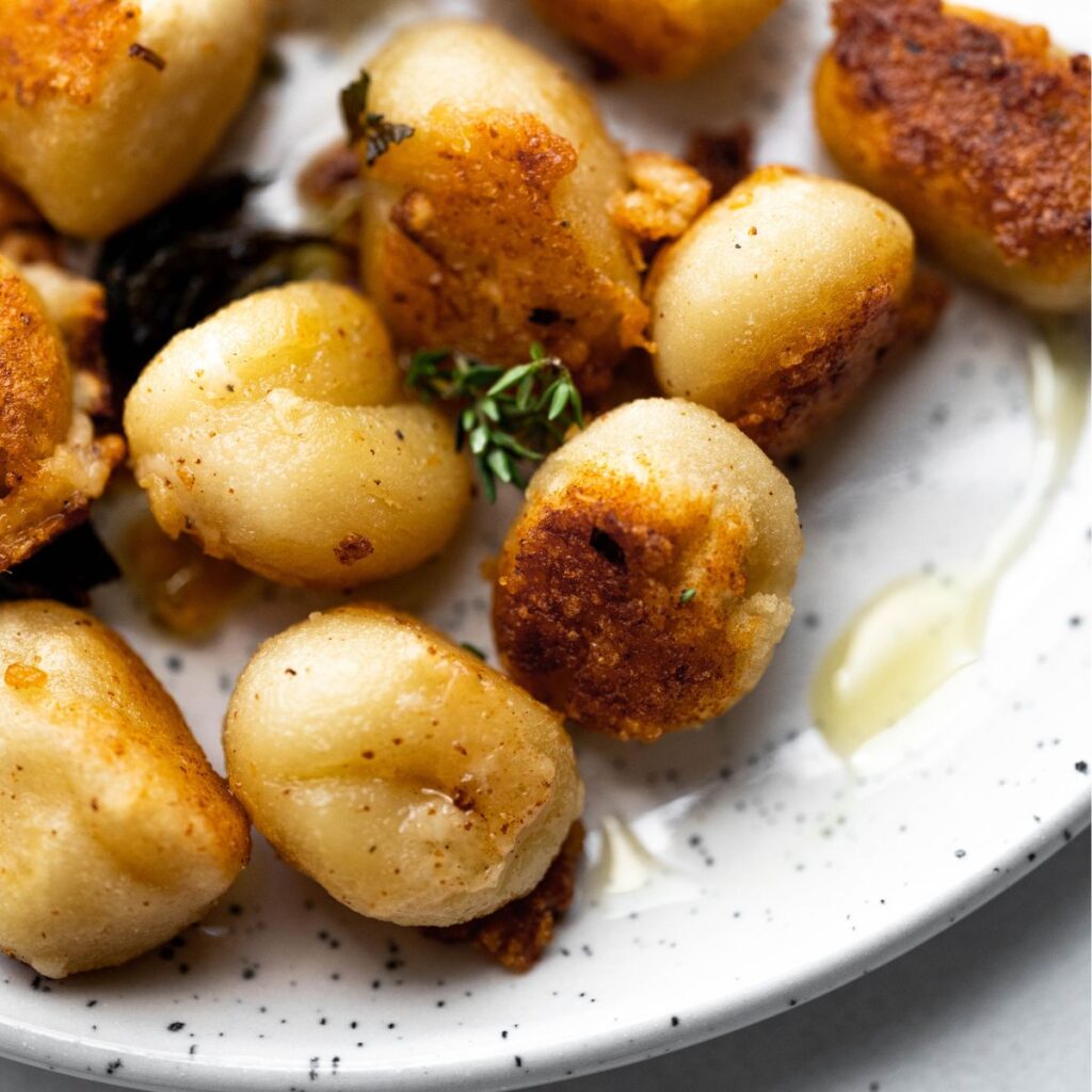 Close up photo of pan fried gnocchi with crispy edges. 