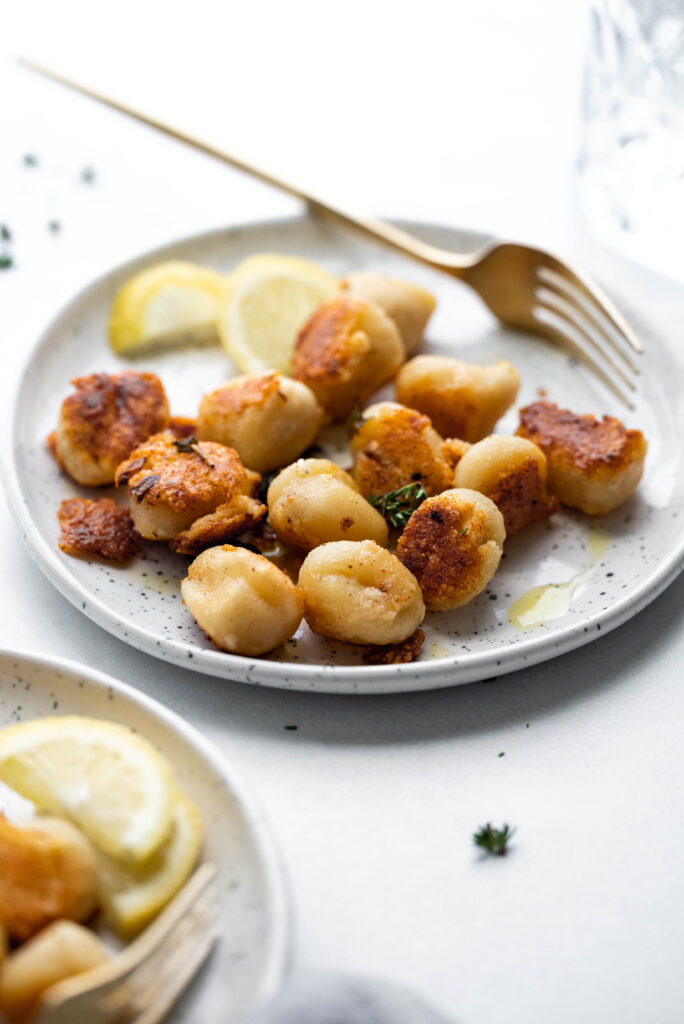 Crispy pan fried gnocchi on a speckled plate. 