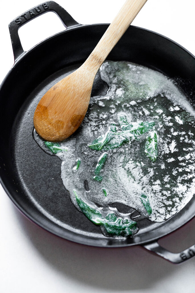 Process shot of melted butter and sage leaves. 