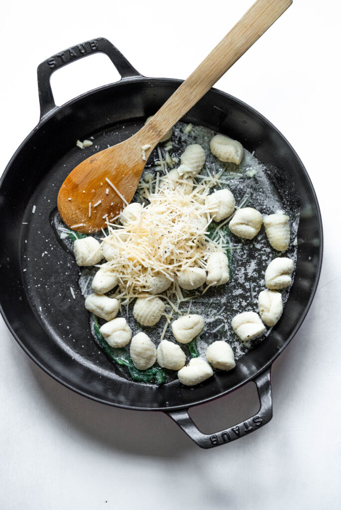 Process shot of gnocchi and parmesan in a pan. 