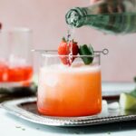 Strawberry mojito mocktail in a short glass with strawberry and mint garnish.