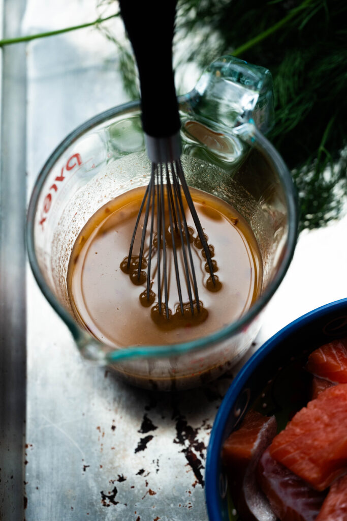 Hot honey dressing in a pyrex with a whisk. 