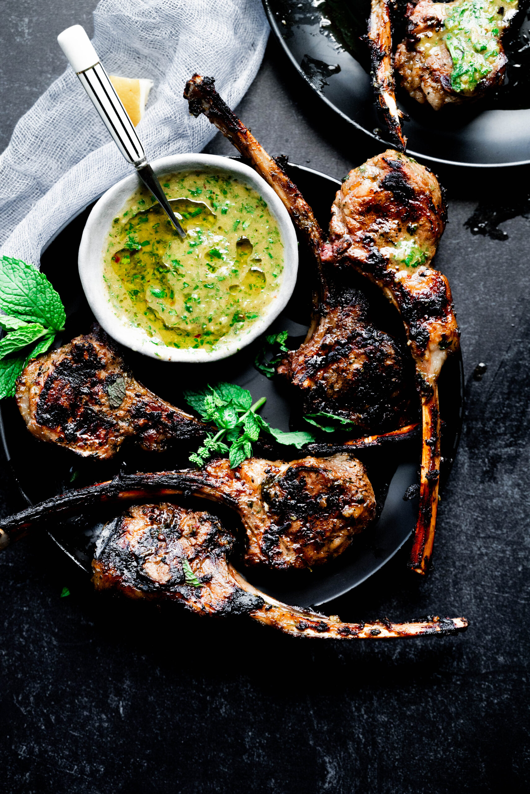 Lamb chops on a black plate on a black background. 