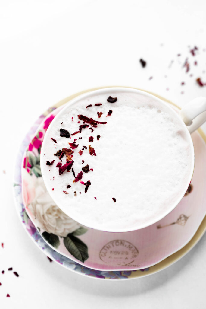Rose tea cup with frothy milk and rose petals. 