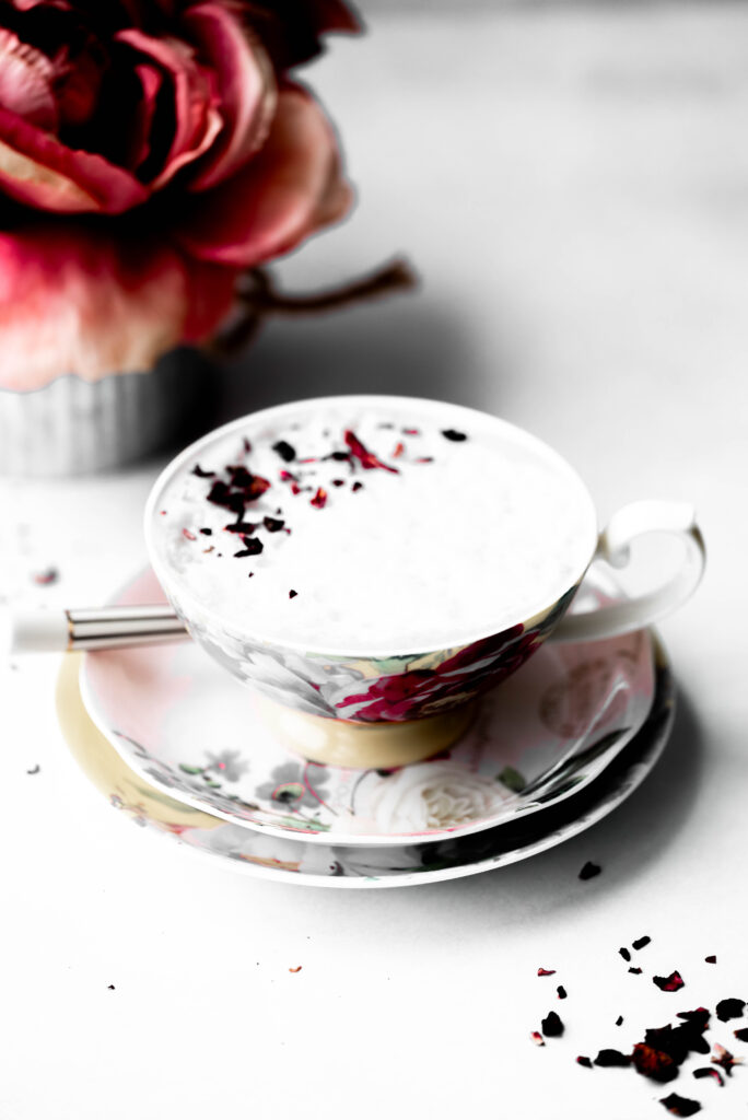 Rose tea cup with flowers in the back. 