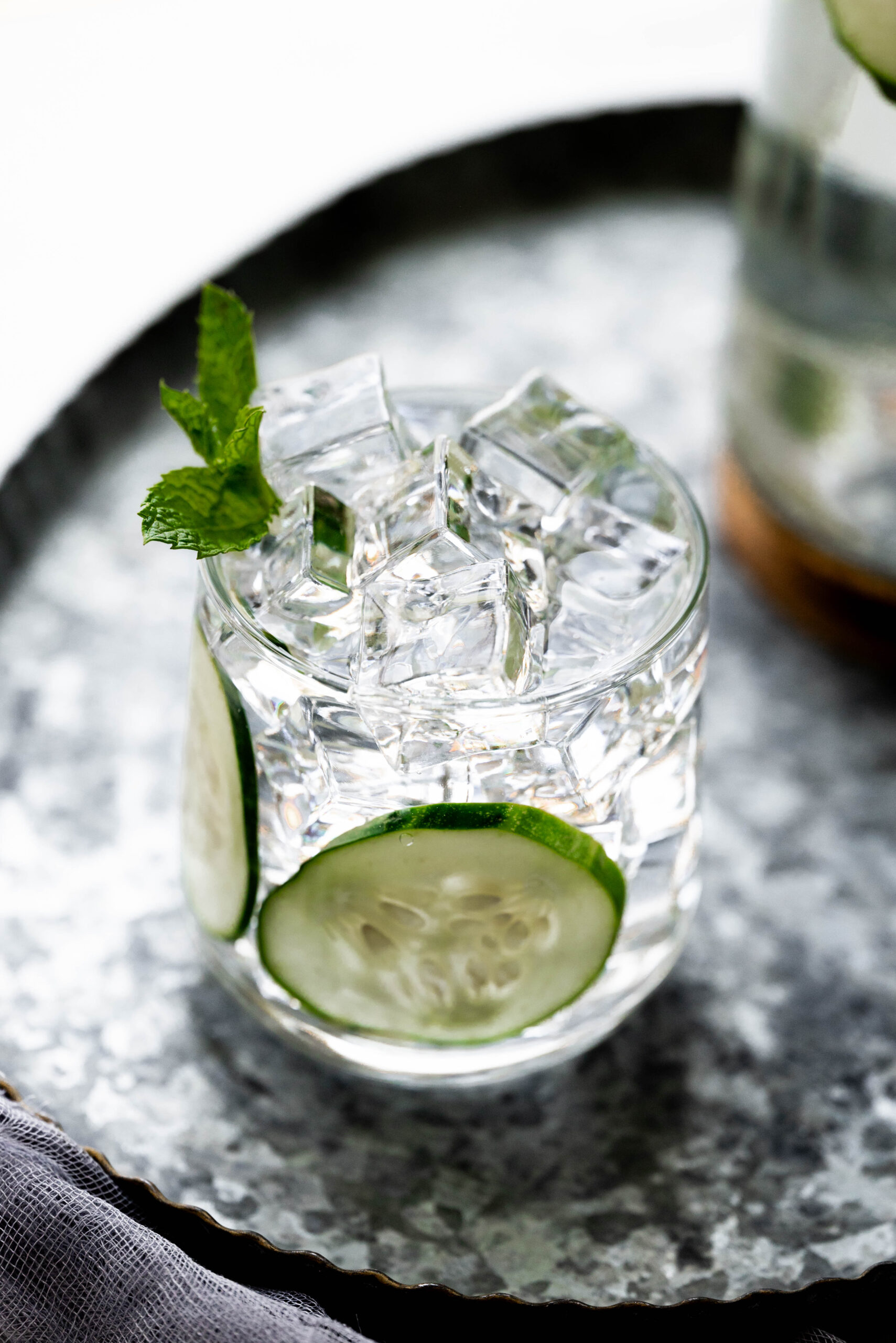 Cucumbers and ice in a glass on a silver plate. 