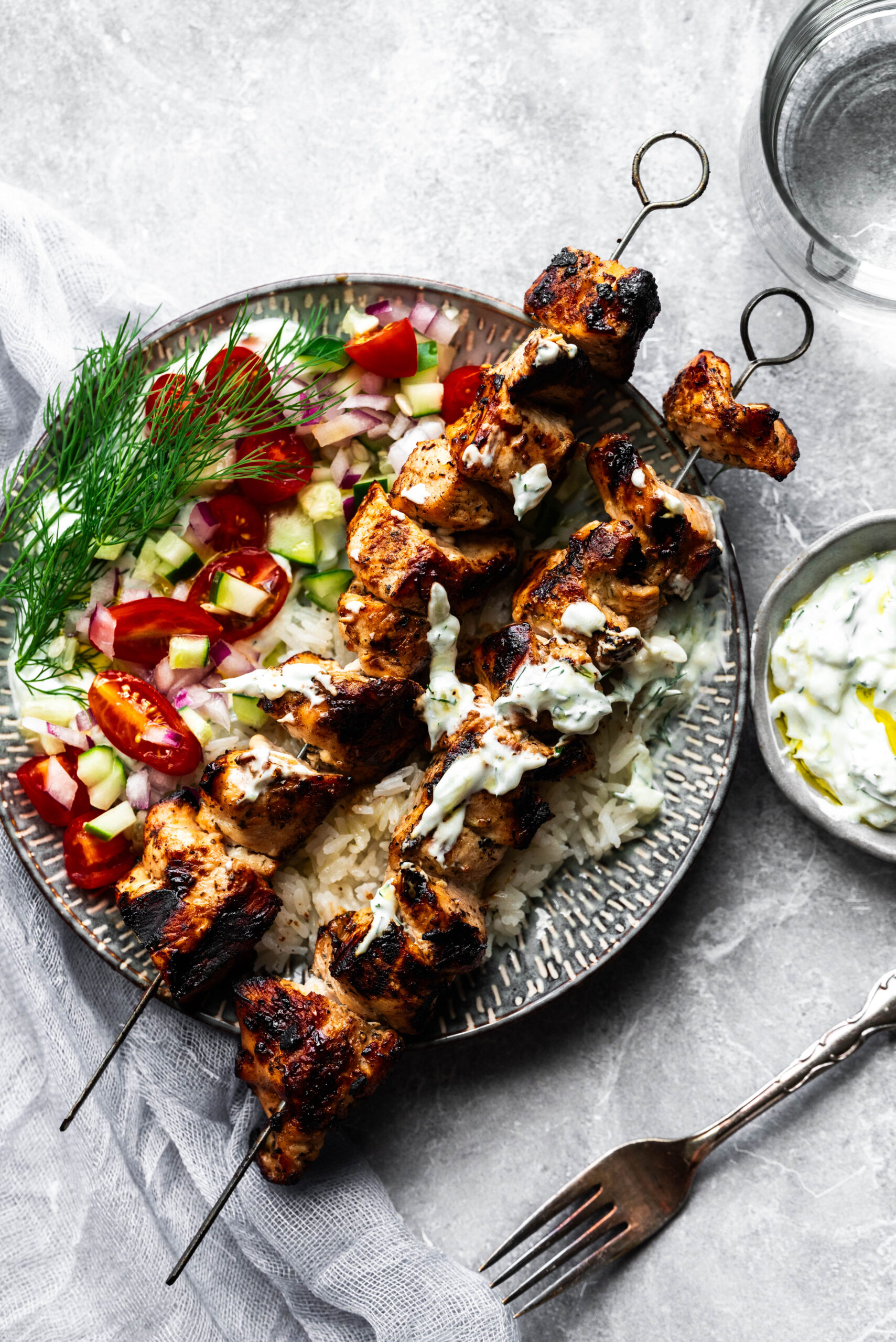 Chicken skewers on a plate with yogurt sauce. 