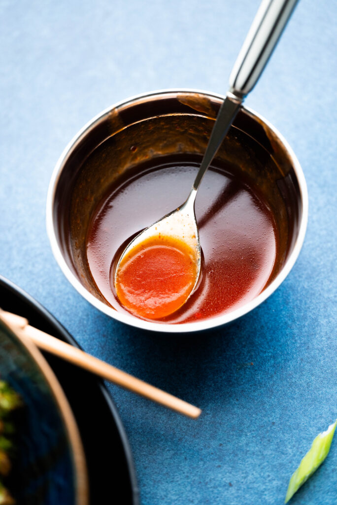 Honey sriracha sauce in a bowl on a blue background. 