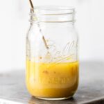 Dressing in a jar with a gold spoon.