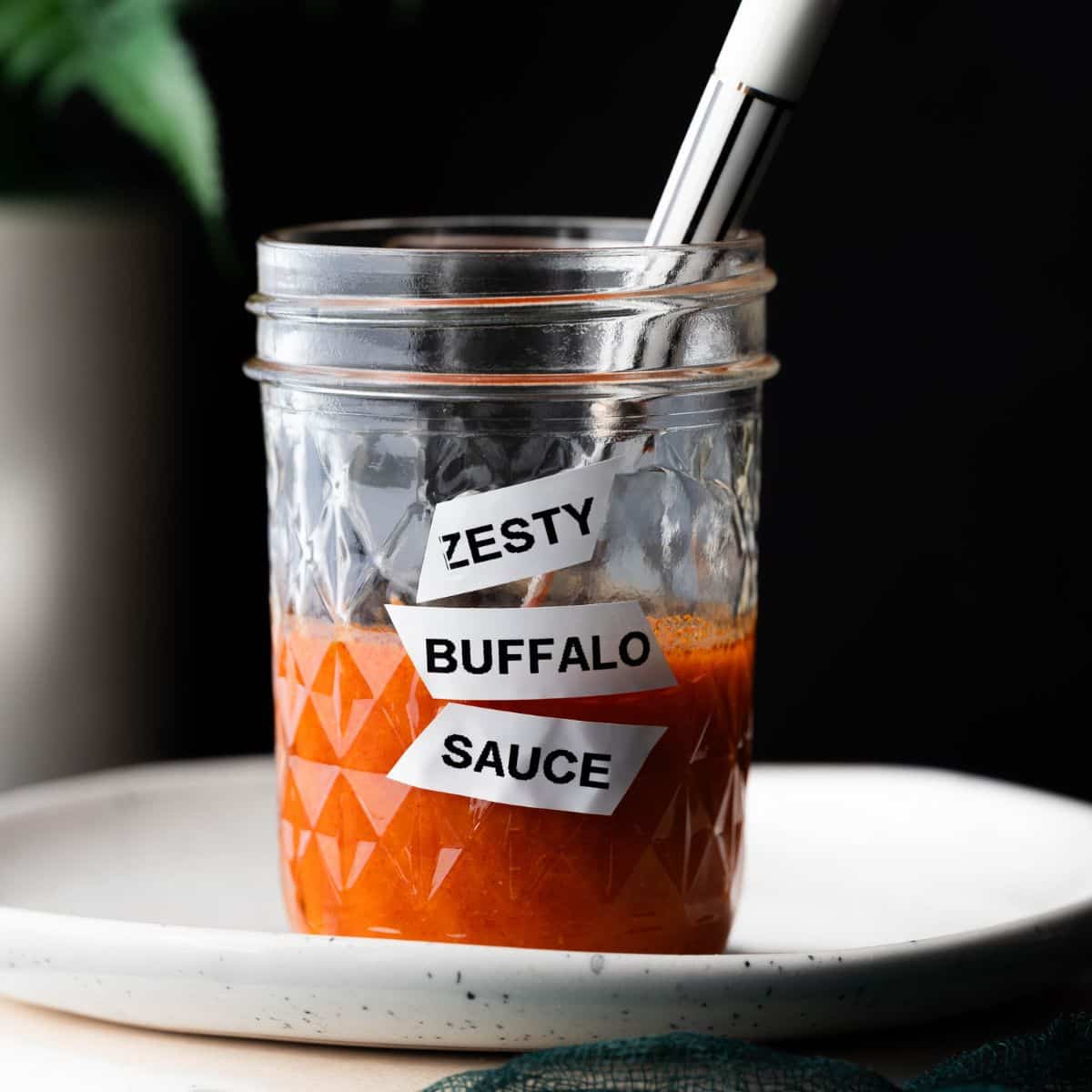 Labeled mason jar "zesty buffalo sauce" on a black background. 