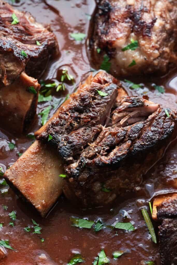 Close up image of dutch oven braised beef short ribs in tomato sauce. 