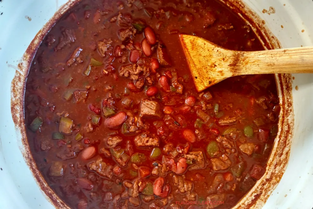 Overhead image of perfect steak chili with a wooden spoon. 