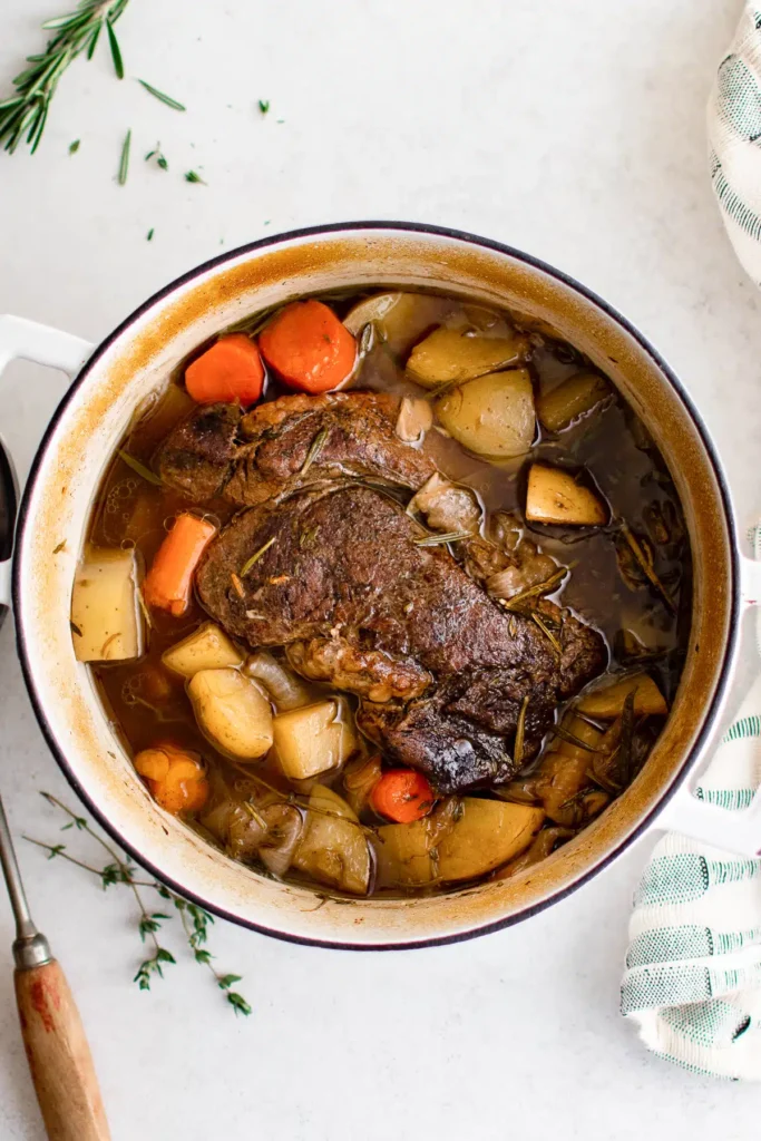 Overhead image of dutch oven pot roast with carrots and potatoes. 