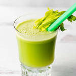 Cold pressed celery juice in a glass on a white background.