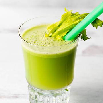 Cold pressed celery juice in a glass on a white background.