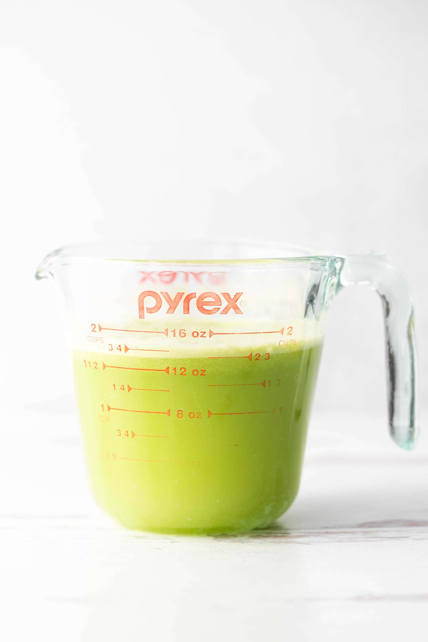Celery juice in a pyrex on a white background. 