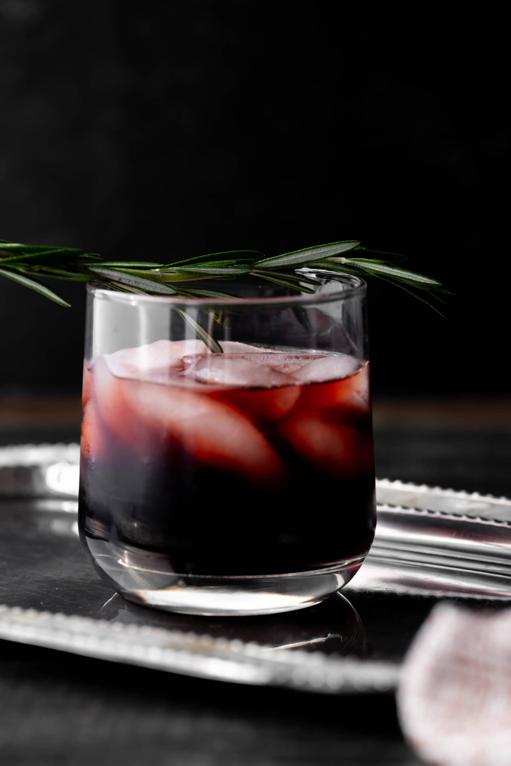 straight shot of a mocktail with a rosemary sprig. 