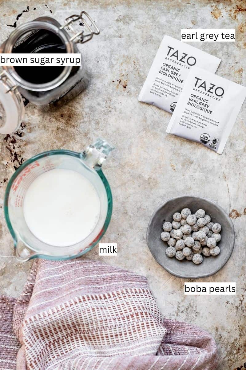 Ingredients needed to make earl grey milk tea on a sheet pan with labels. 