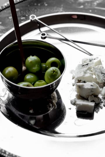 Blue cheese and olives on a plate with cocktail picks. 
