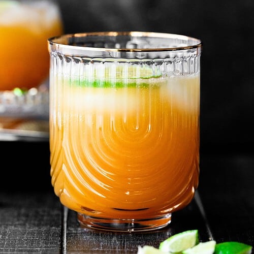 Hero image of a mango mocktail with a lime garnish.