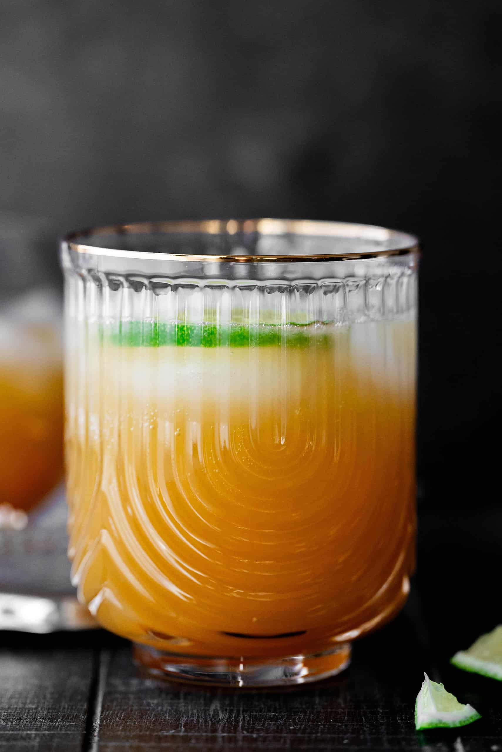Hero image of mango mocktail in a short glass with a black background. 