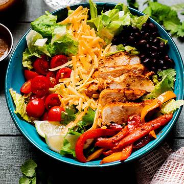 Chicken fajita salad in a blue salad bowl.