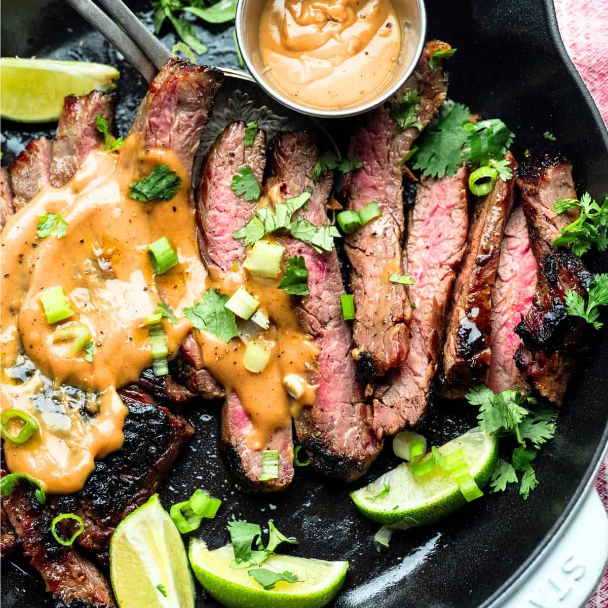 Hero image of seared flank steak sliced with peanut sauce on top. 
