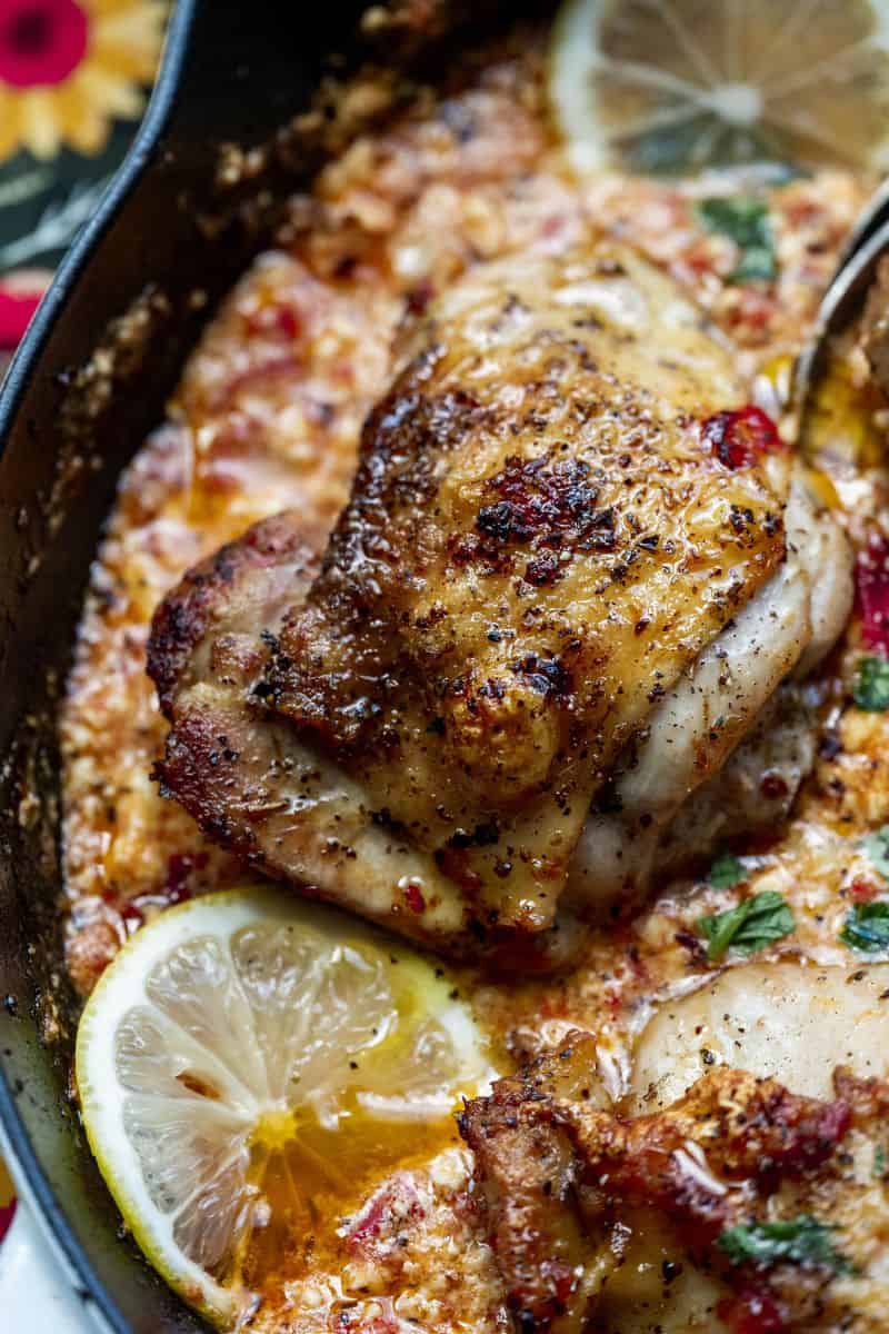 Close up image of a baked feta chicken thigh on a spoon. 