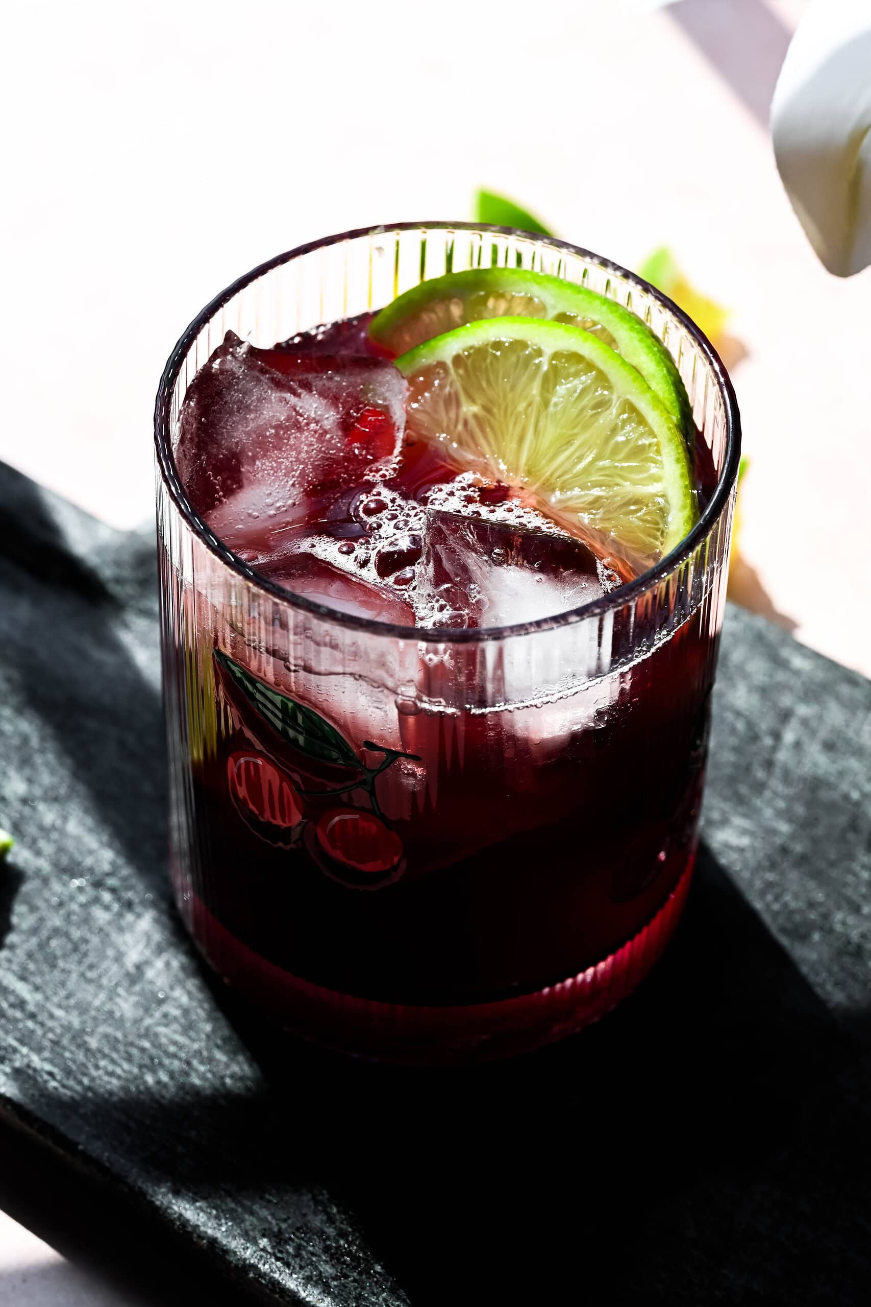 Overhead image of a dark cherry mocktail with lime wedges. 