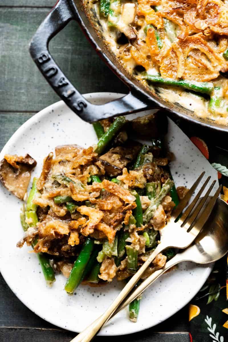 Green bean casserole on a plate with gold silverware. 
