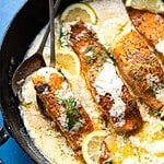 Overhead image of salmon in a black pan with a blue background.