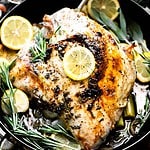 Overhead image of a roast turkey breast in a dutch oven with lemon and rosemary.