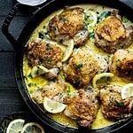 Overhead image of bone-in, skin-on Chicken thighs with lemon on the side.