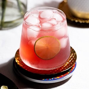 Hero image of the drink with a lime garnish on a coaster.