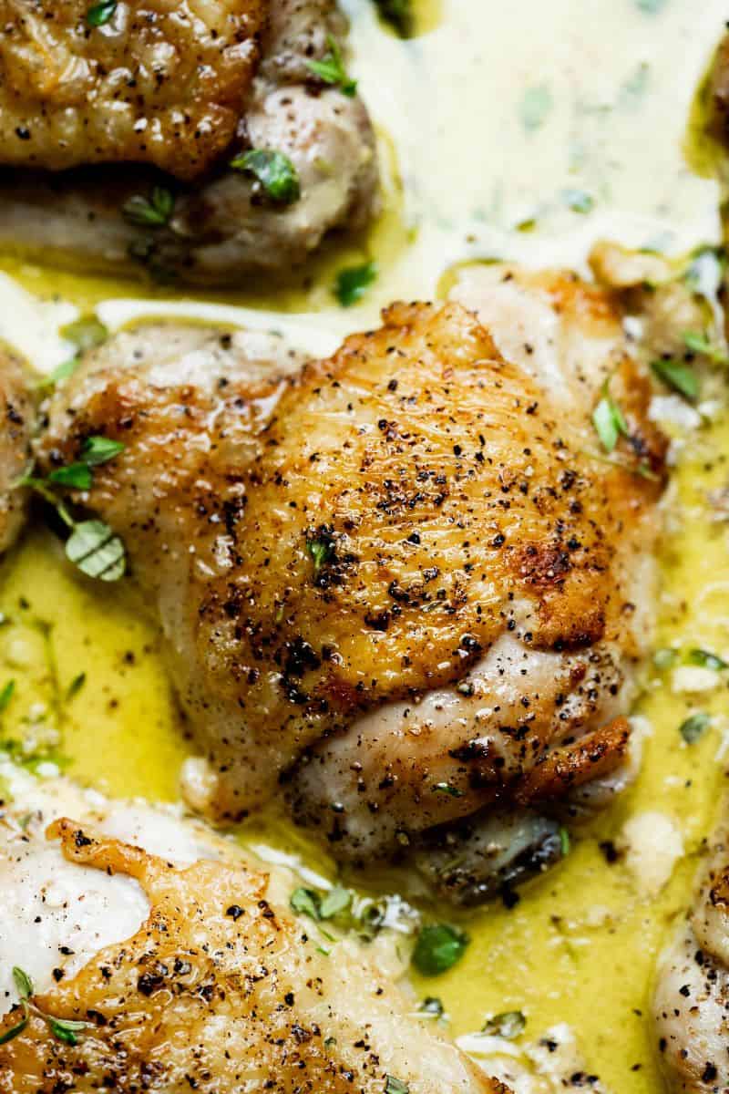 Close up of skin-on chicken thigh in mustard creamy sauce.