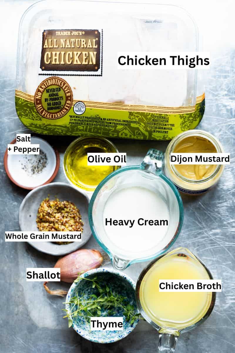 Ingredients on a sheet pan with labels to make Creamy Mustard Chicken Thighs in one skillet.