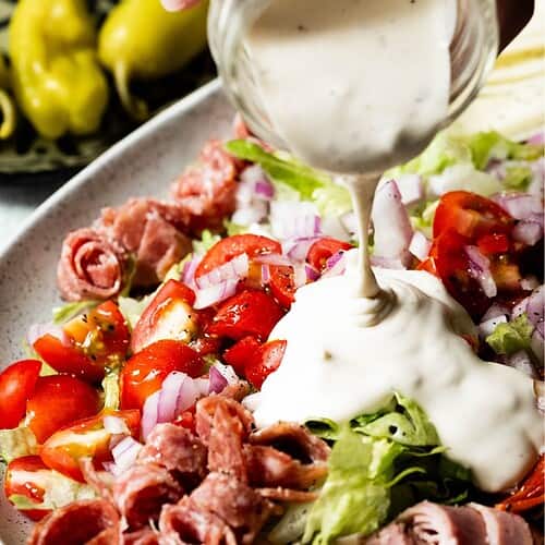 dressing being poured onto a salad