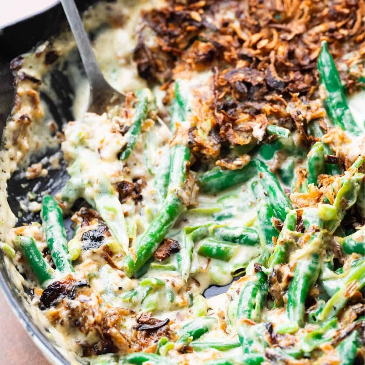 Green bean casserole made with Boursin cheese with a silver spoon. 