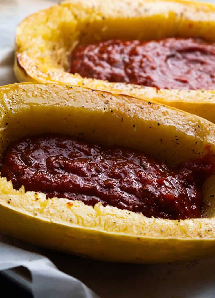 Squash with sauce on a sheet pan.